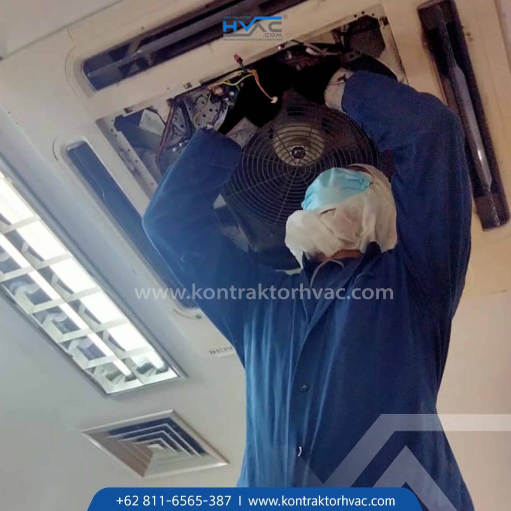 Teknisi sedang membersihkan bagian dalam unit AC cassette dari bawah
