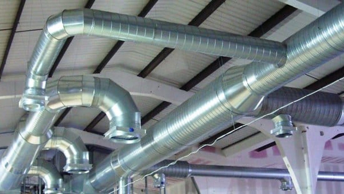 Jalur ducting spiral dan ducting persegi terpasang rapi di bawah atap sebuah bangunan